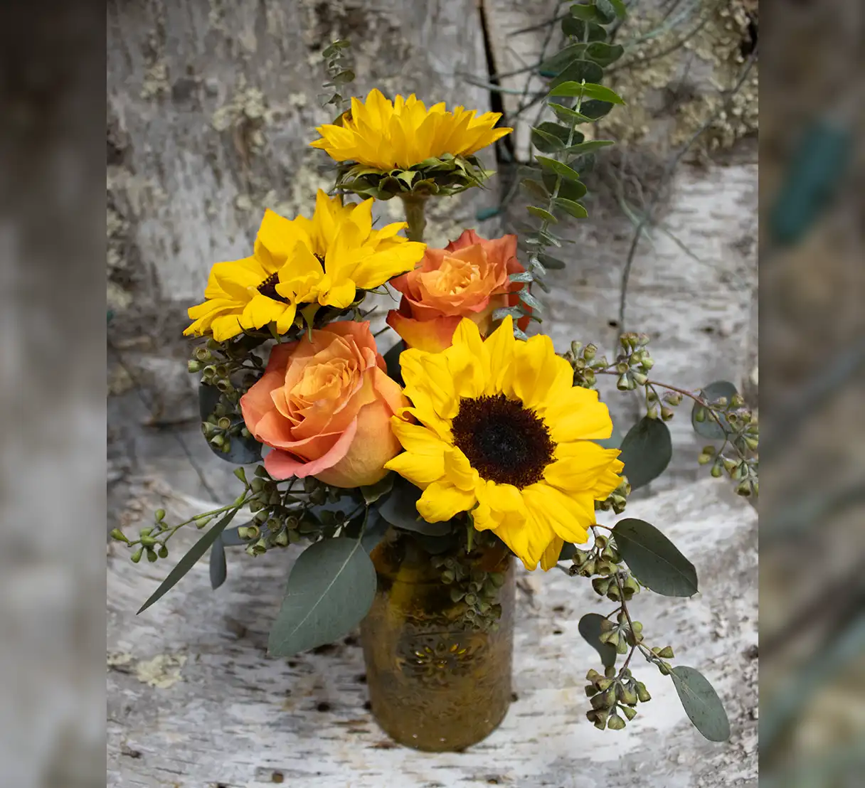 This cheerful arrangement features vibrant yellow sunflowers paired with classic roses, creating a stunning contrast of warm tones.